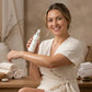 Woman in a white robe holding a skincare product in a spa-like setting