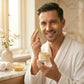 Man applying cream to his face with a jar of cream in a bathroom setting