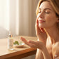 Woman applying skincare product with a dropper bottle on a wooden table.