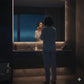 Person standing in a bathroom looking into a mirror with a night sky reflection.