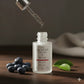 Skincare serum bottle with dropper and blueberries on a wooden surface