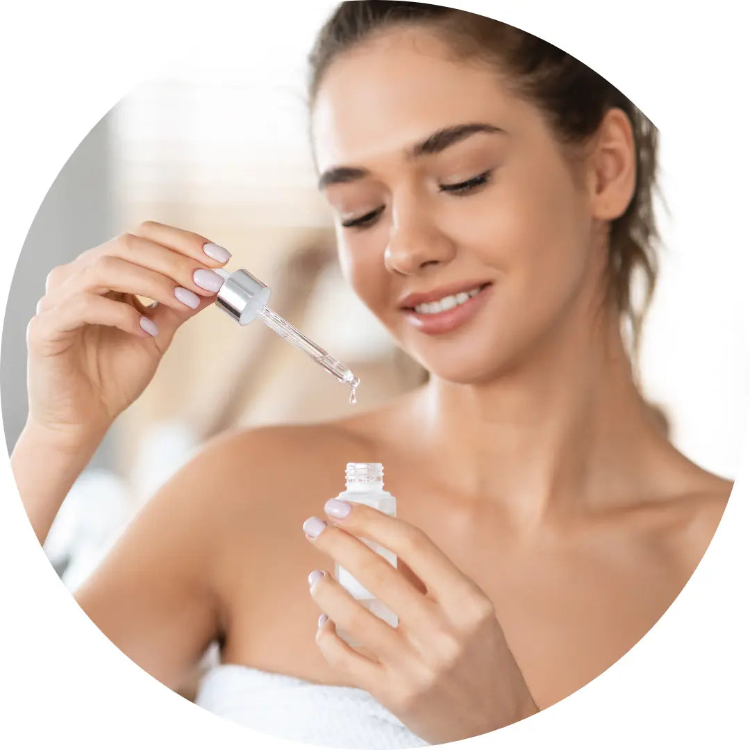 woman using  Buddha Beauty Vegan facial serum from a dropper bottle