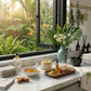 Cosmetic products on a marble counter with a window view of greenery